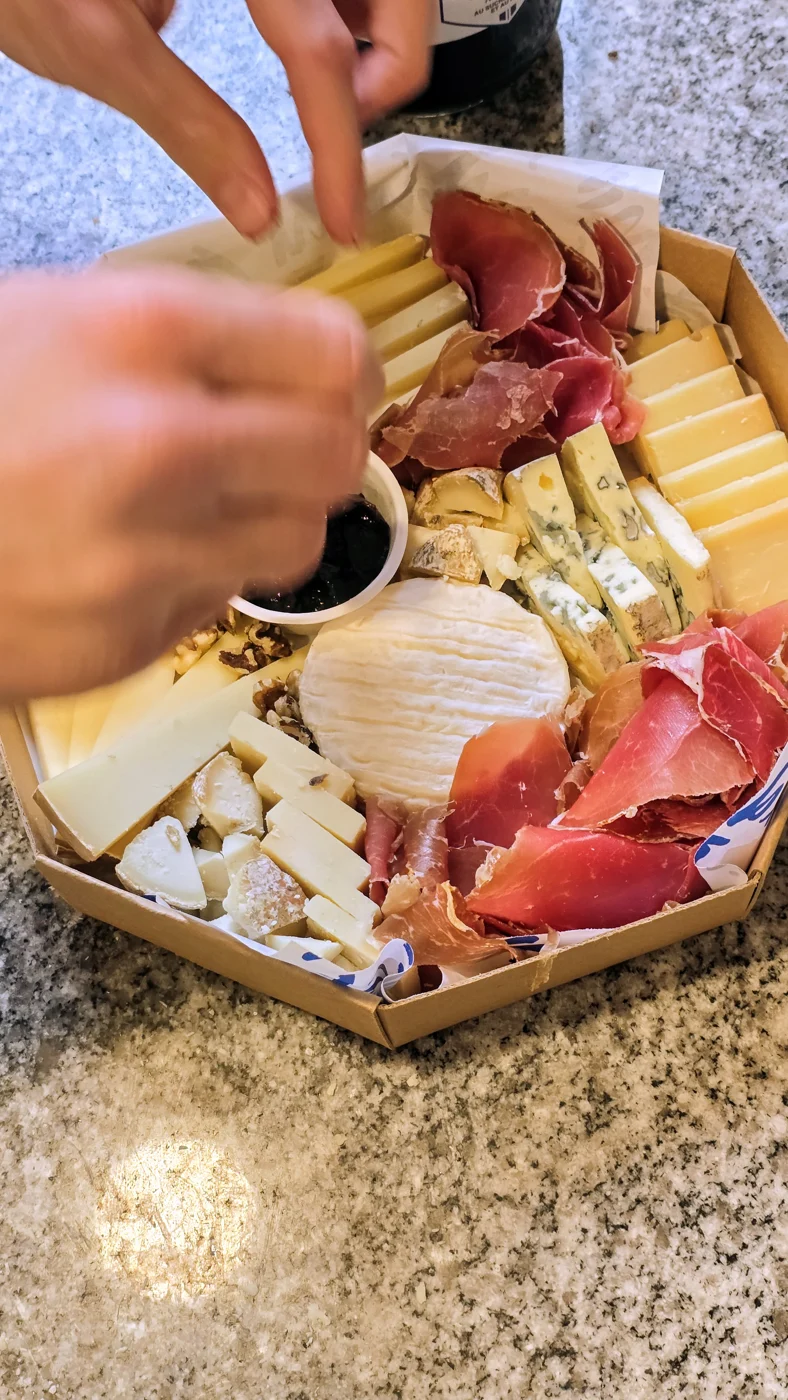 Des mains disposent les fromages sur un plateau octogonal Mirga.
